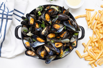 Belgian mussels with potato fries on white marble table flat lay view 