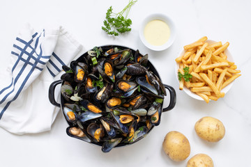 Belgian mussels with potato fries on white marble surface flat lay view 