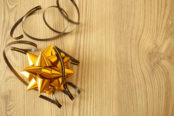 Golden star shaped festive decoration with ribbons on rustic wood