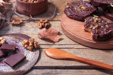 Slices of apples in chocolate, caramel glaze and walnuts on skewers on a wooden background