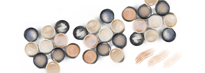Close-up of makeup  jars filled with loose cosmetic face powder different shades on the white background isolated. Panoramic banner with free space for text mockup