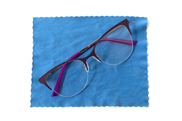 Stylish glasses lie on a blue cloth for cleaning. Isolated