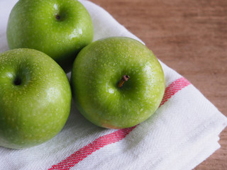 Green apple on fabric wooden background.