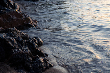 Obraz premium sunrise light over stones, sand and water