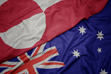 waving colorful flag of australia and national flag of greenland.