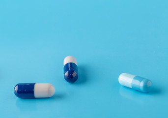 Various white-blue medication capsules. Blue background with text space