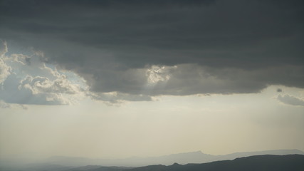 Mountains and dark clouds over it with sun behind the clouds