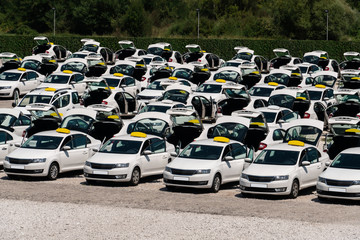 Many taxi cars stand in rows in a parking lot