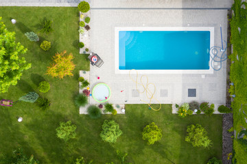 Aerial shot of green lawn and garden with a swimming pool in the courtyard.