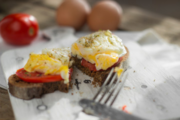 Poached egg on sourdough toast, with grilled tomatoes. A healthy, delicious breakfast or brunch