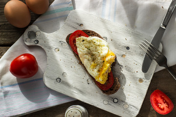 Poached egg on sourdough toast, with grilled tomatoes. A healthy, delicious breakfast or brunch