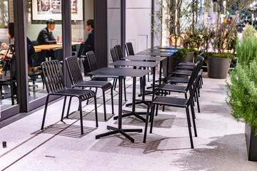 Black shiny steel chairs and wooden tables in indoor industrial and modern style canteen