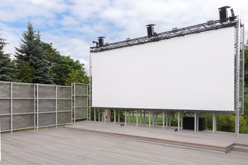 Outdoor empty movie cinema theater with white projection screen in the park, waiting for the show with copy space