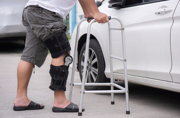 Senior man opens the car door with a walker on the road
