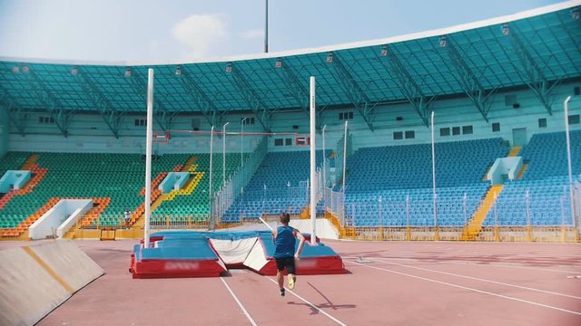 Pole vault - an athletic man runs up holding a pole and jumping over the bar and pushes it away