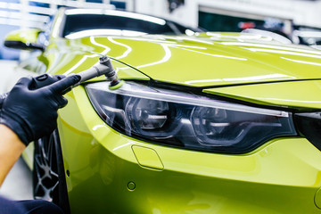 Car detailing - Worker with orbital polisher in auto repair shop.