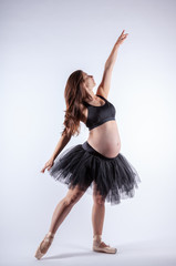 Young beautiful pregnant ballerina with black dress.