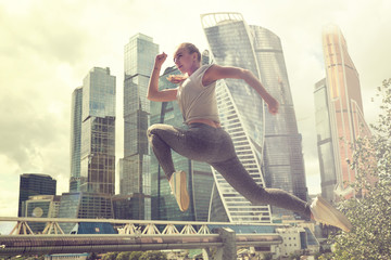 Young woman with fit body jumping and running. Female model in sportswear exercising outdoors.
