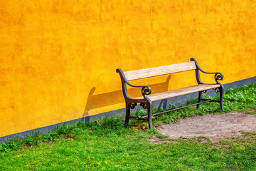 wooden bench near yellow wall