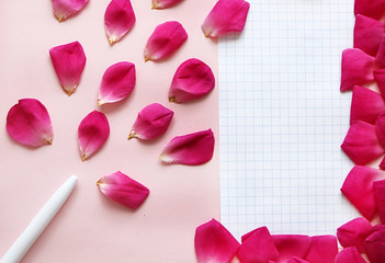 Pen, rose petals and piece of paper on the pink background. Concept of beauty blogger work. Place for text. Flat lay, top view
