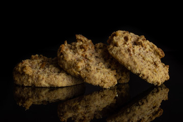 Group of three whole sweet oat crumble biscuit isolated on black glass