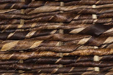Finely woven dark strands of wicker as seen with up close with a macro lens. Full frame image with rough textures.
