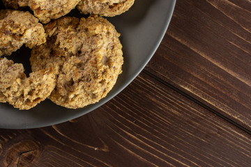 Lot of whole oat crumble biscuit on grey ceramic plate flatlay on brown wood
