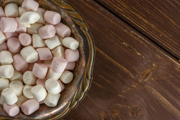 Lot of whole sweet fluffy marshmallow copyspace in old iron bowl flatlay on brown wood