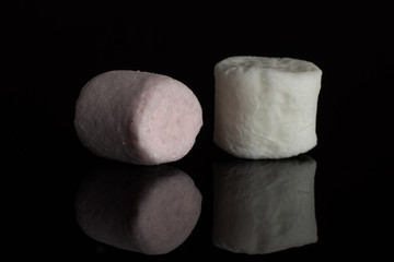 Group of two whole pink and white sweet fluffy marshmallow isolated on black glass