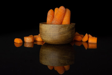 Group of four whole lot of pieces of stale  orange stale baby carrot baby in wooden cup isolated on black glass