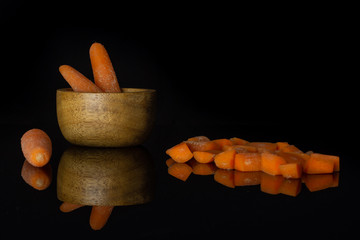 Group of three whole lot of pieces of stale  orange stale baby carrot baby in wooden cup isolated on black glass
