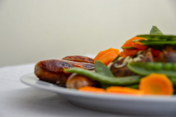 Dinner of a  jacket potato and vegetables and sausages