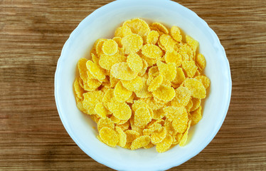 white bowl of corn flakes on wooden background