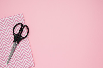 Scissors and fabrics for sewing on pink background with copy space