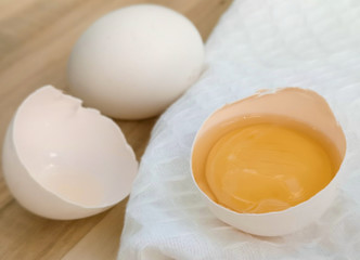 Eggs - whole and broken - lie on wooden background