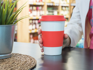 Woman holds a cup of coffee in coffee shop. 