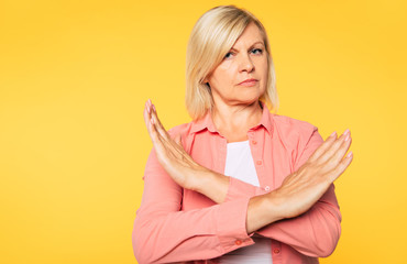 Close up photo of serious and confident senior woman while she shows stop gesture on camera 
