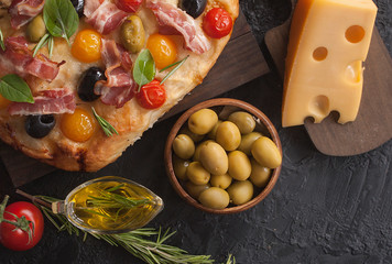 Traditional Italian Focaccia with tomatoes, olives, bacon and rosemary - homemade flat bread Focaccia. The view from the top. Copy space.