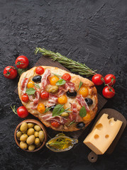 Traditional Italian Focaccia with tomatoes, olives, bacon and rosemary - homemade flat bread Focaccia. The view from the top. Copy space.