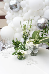 Table with glasses on a background of white balls and flowers in a white style