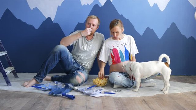 young couple with a dog eating popcorn near the mountains picture on the wall