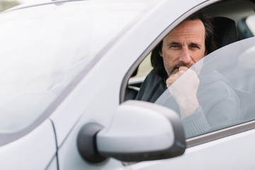 Handsome adult man sitting thoughtfully in a car.