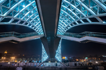 Pedestrian bridge of peace over the Mtkvari (Kura) River in Tbilisi at night.