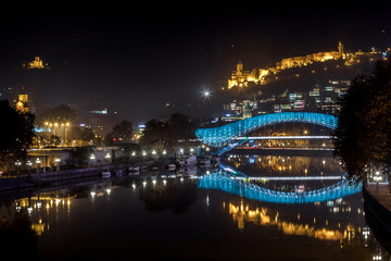 Pedestrian bridge of peace over the Mtkvari (Kura) River in Tbilisi at night. Narikala fortress.