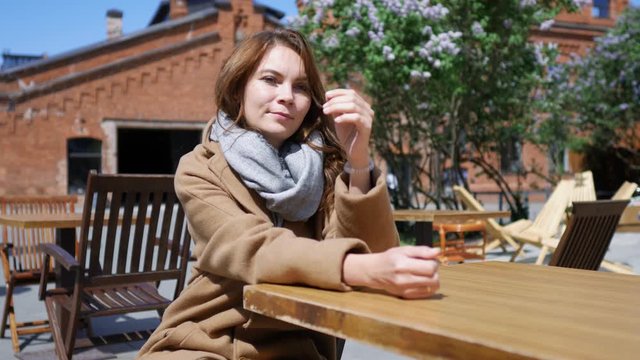 charming woman is waiting at a table of a street cafe
