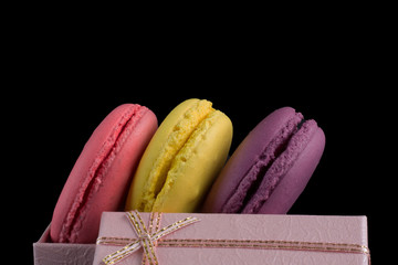 Macaroons box top view. Sweet french macaroons cake on the black background.