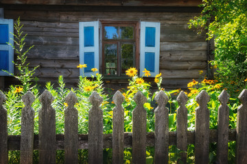 Garden with flowers in front of the old, wooden hut.