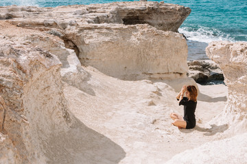 Beautiful woman meditates and relax in the rocks near the sea.