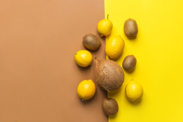 Bunch of raw organic lemons kiwi coconut on duotone yellow brown background. Creative flat lay food poster. Vegan vitamins summer tropical fruits cocktail ingredients. Poster with copy space