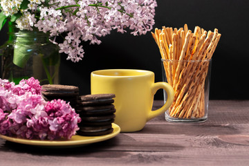 Tea party, yellow cup, chocolate cookies decorated with Syringa flowers